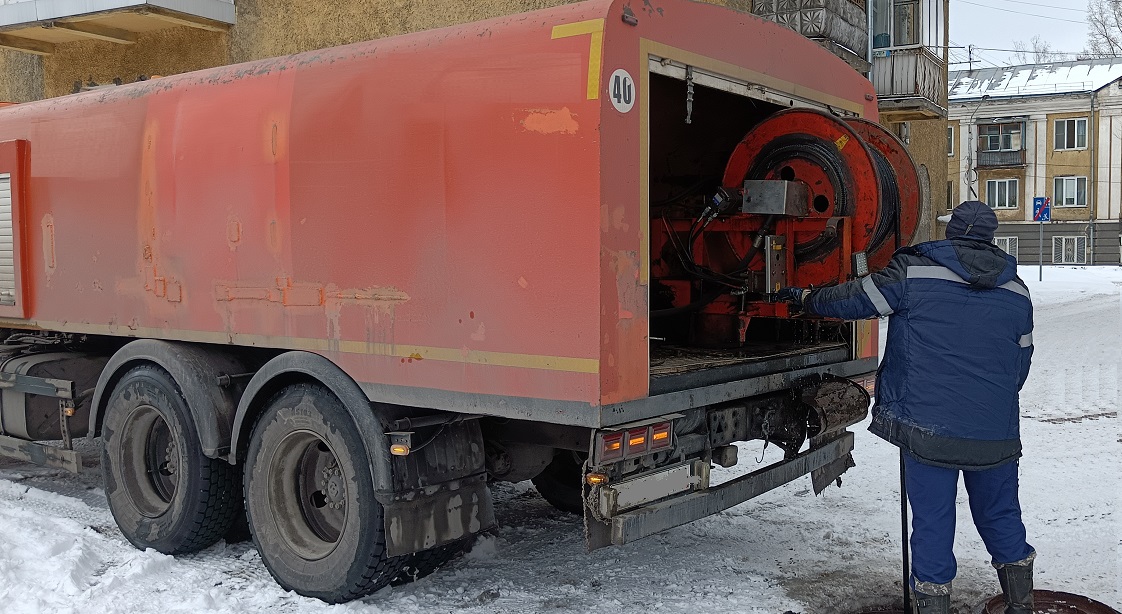 Каналопромывочная машина и работник прочищают засор в канализационной системе в Железногорске